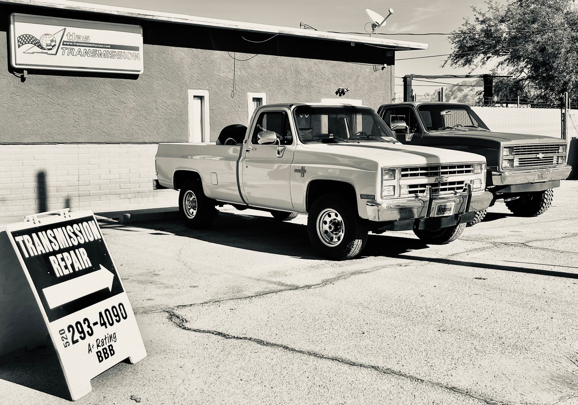 A black and white photo of trucks parked in front of a building