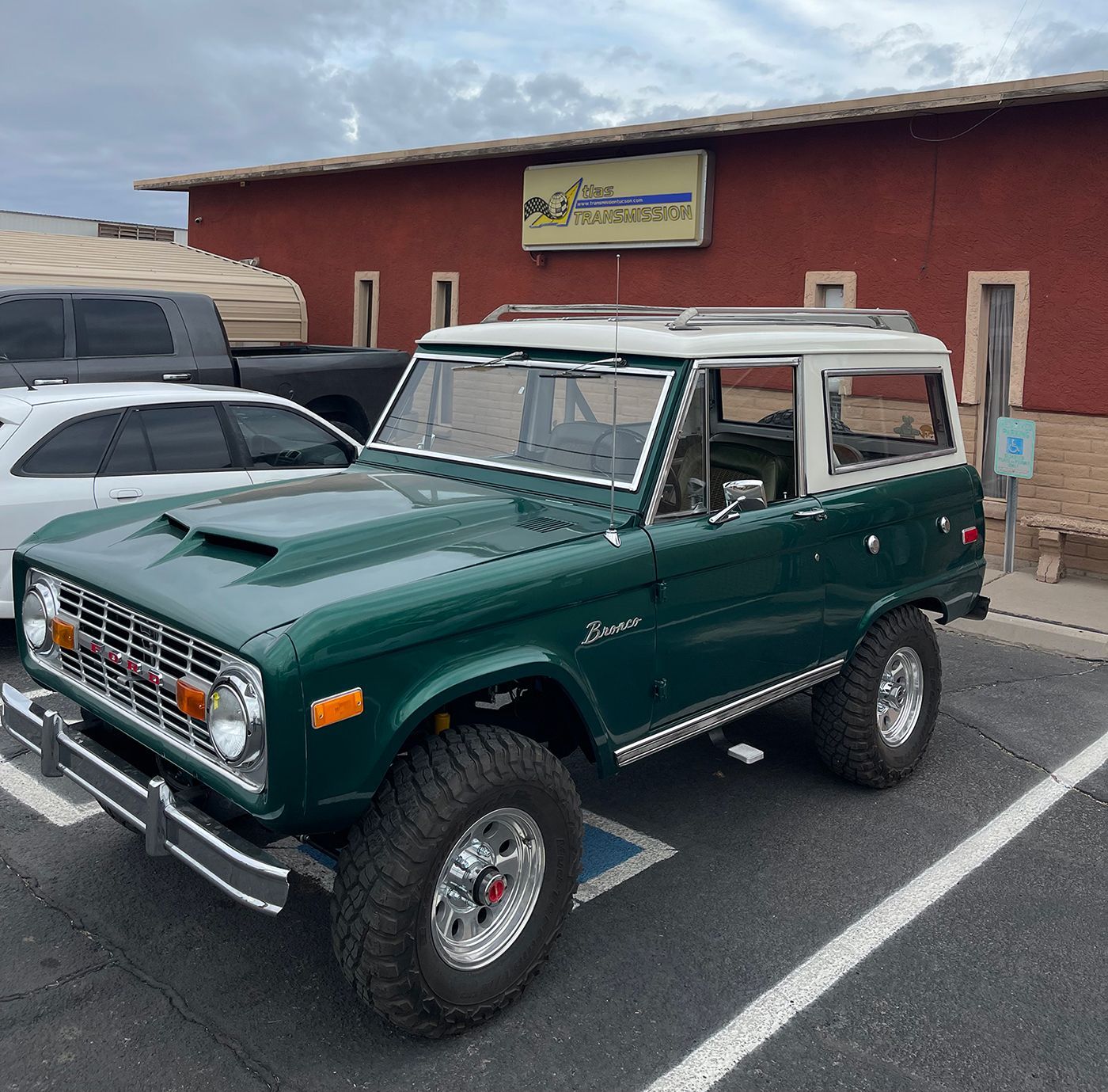 A green jeep is parked in front of a red building