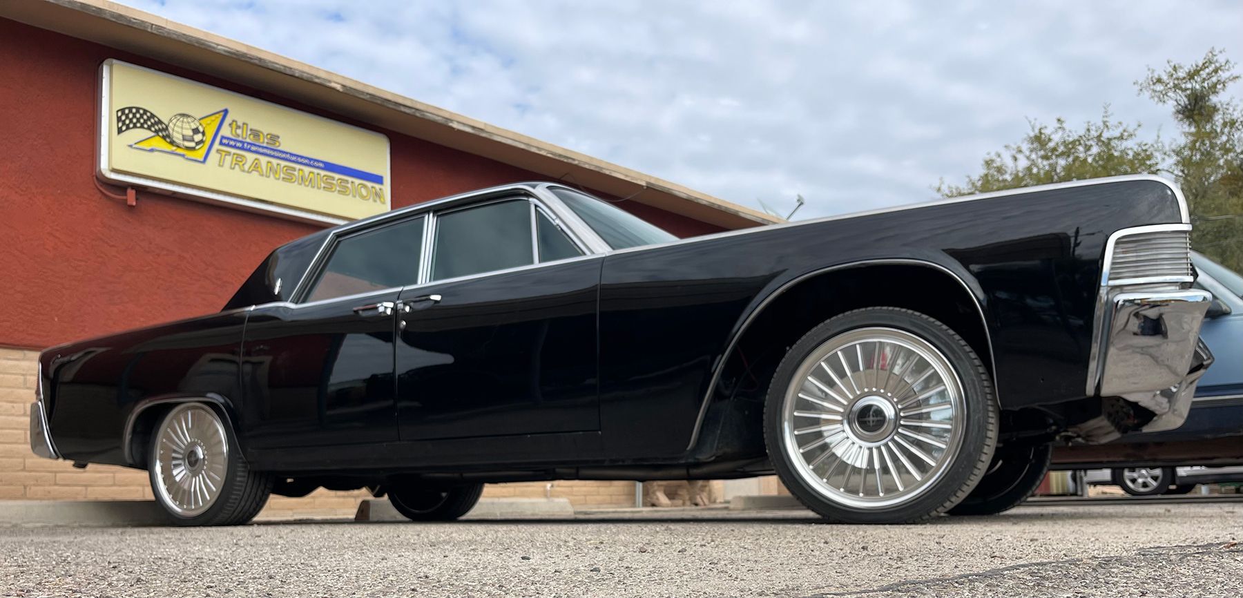 A black car is parked in front of a building.