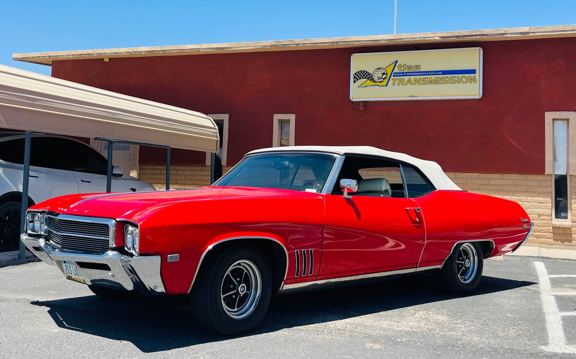 A red car with a white top is parked in front of a building.