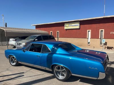 A blue car is parked in front of a red building.