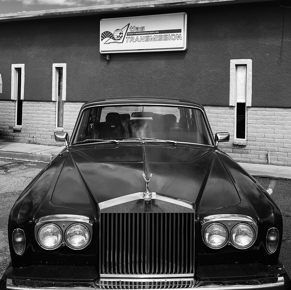 A black and white photo of a rolls royce parked in front of a building