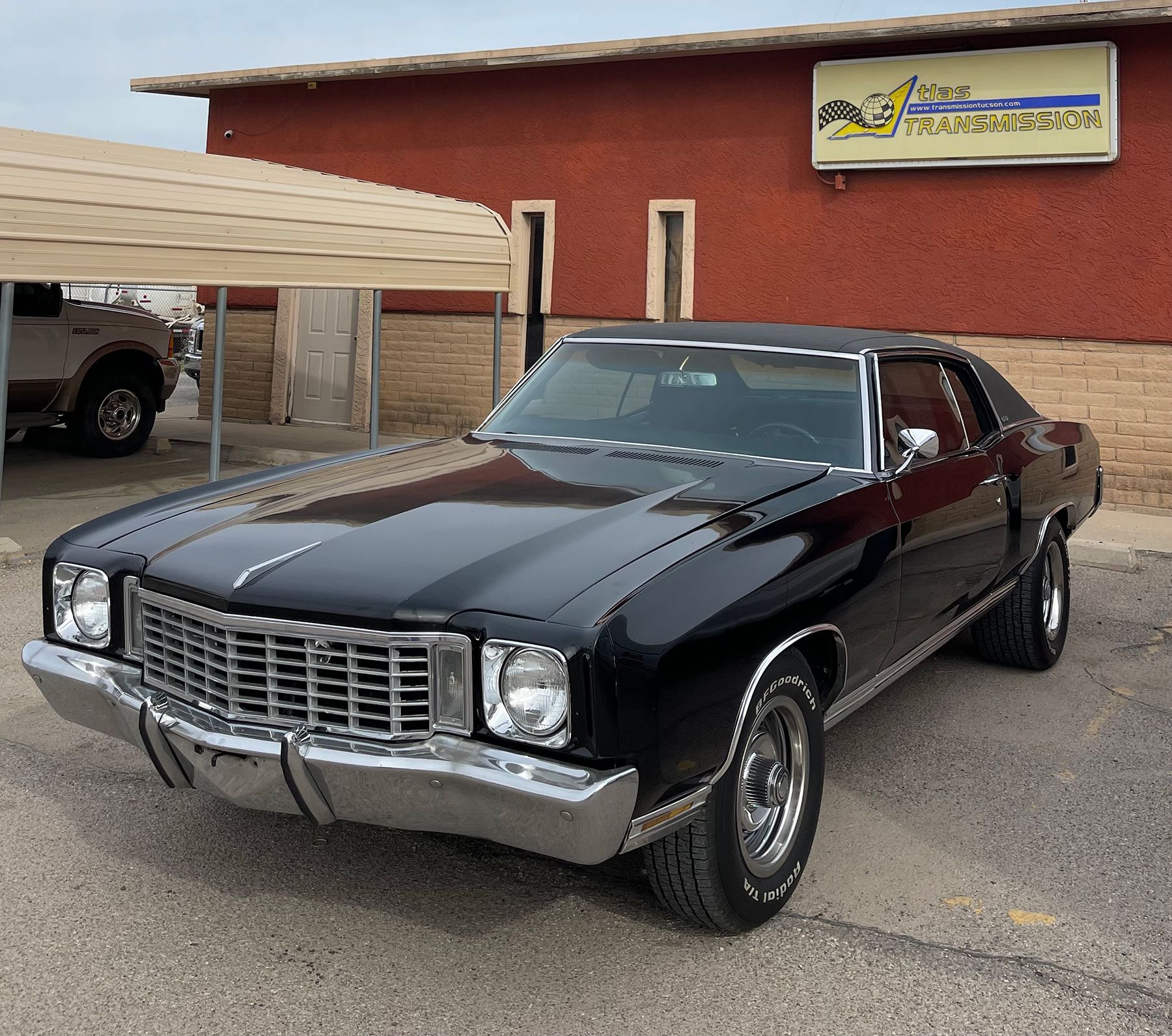 A black car is parked in front of a car dealership