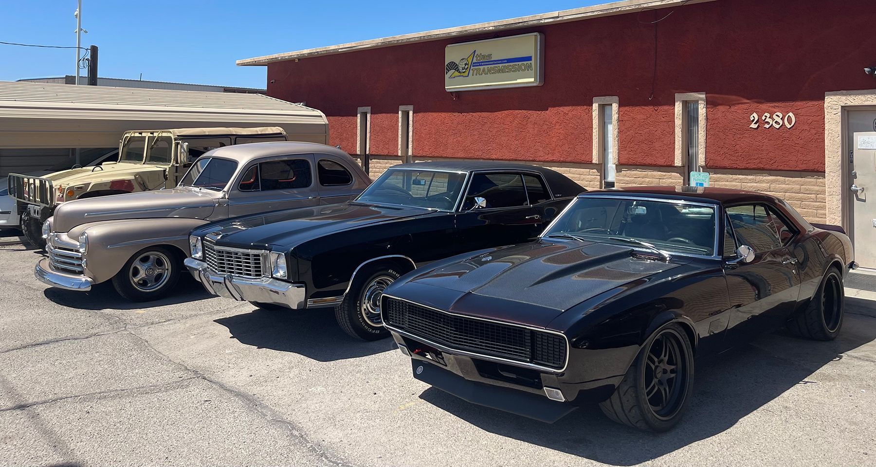 Three old cars are parked in front of a building.