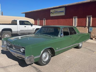 A green car is parked in front of a red building.
