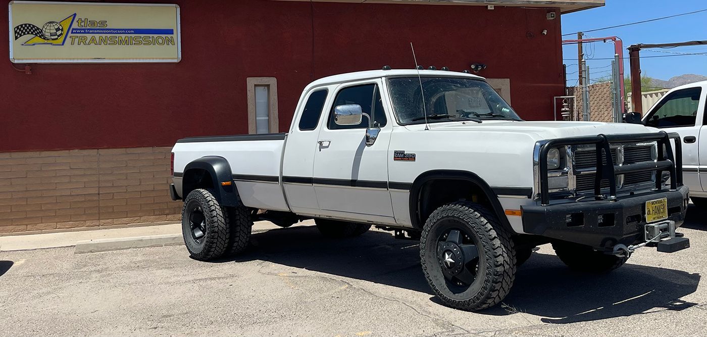 A white truck is parked in front of a red building.