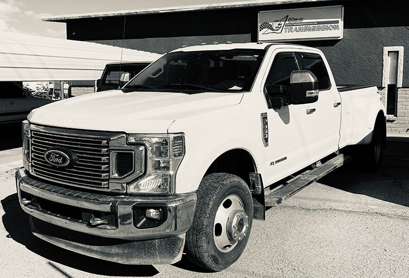 A white ford truck is parked in front of a building.