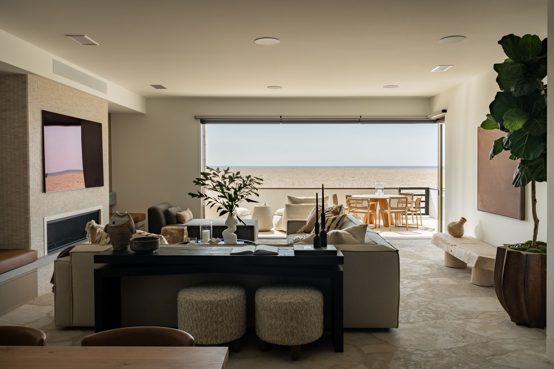 A modern living room with a fireplace, a mounted television, a circular black coffee table, and comfortable seating.