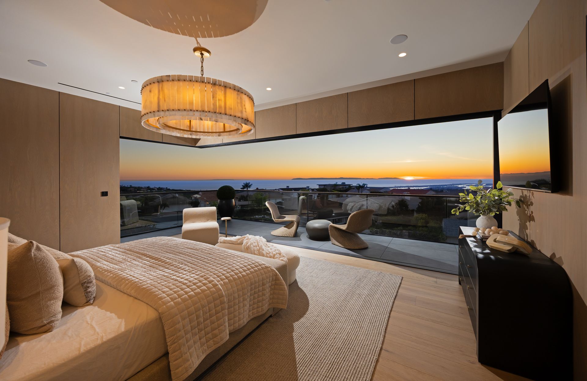 Modern white house exterior at dusk with a swimming pool, glowing landscape lighting, and patio seating on synthetic turf.