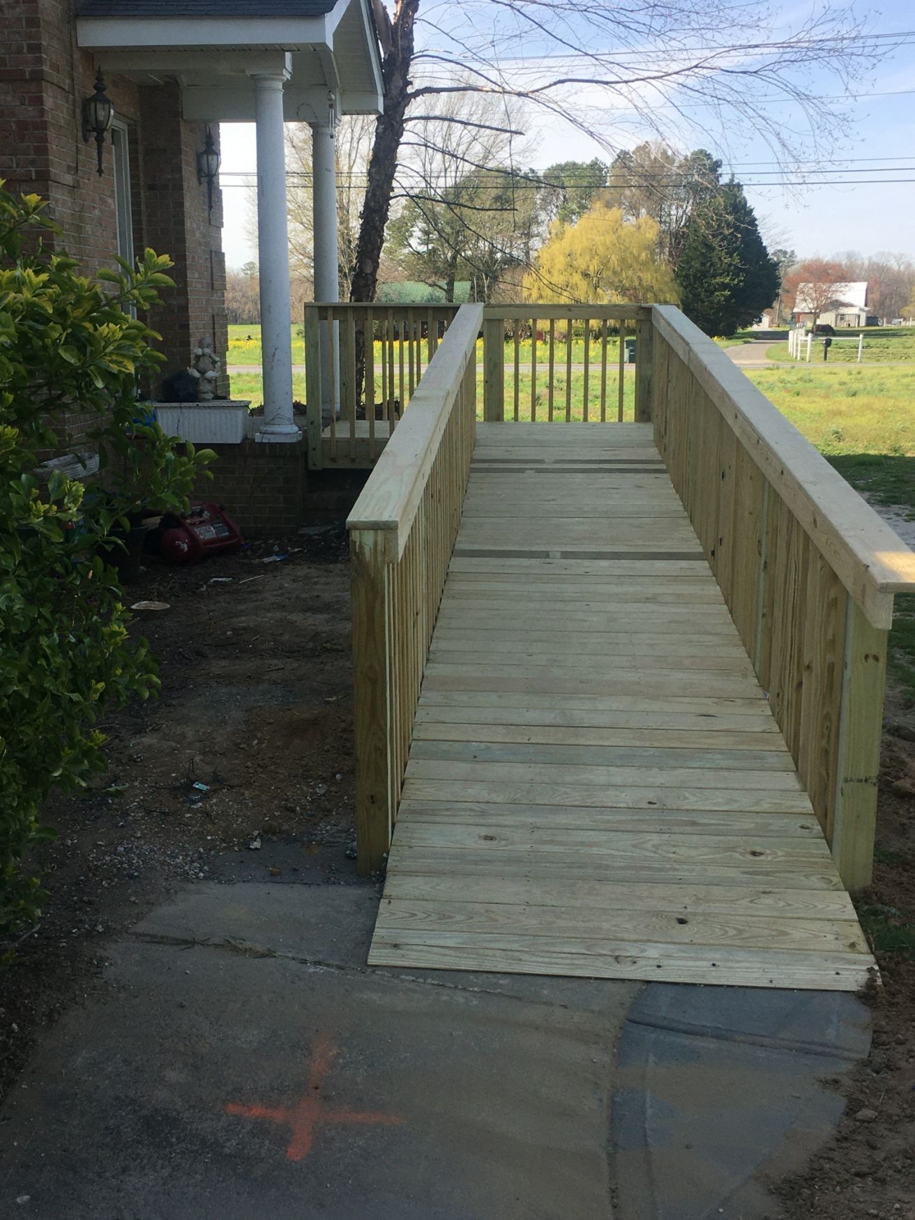 Wooden accessibility ramp with side rails leading up to a porch beside a house