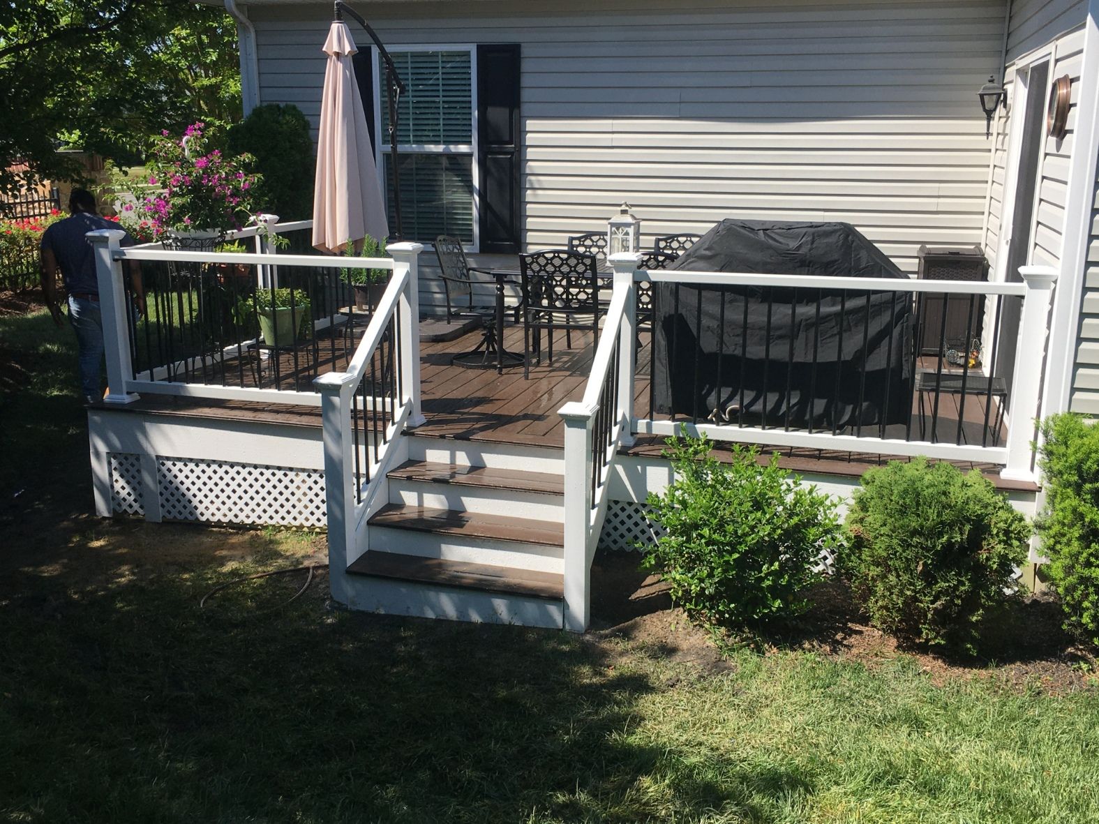 A white wooden archway with columns separates two rooms with beige walls and hardwood flooring.