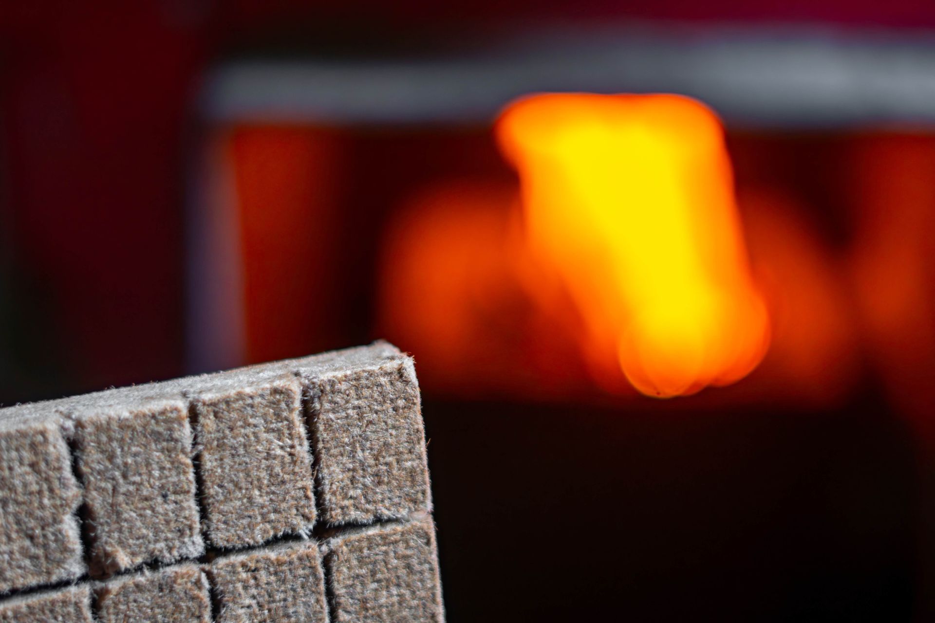 Close-up of a gray brick beside a glowing orange fire in a dark fireplace