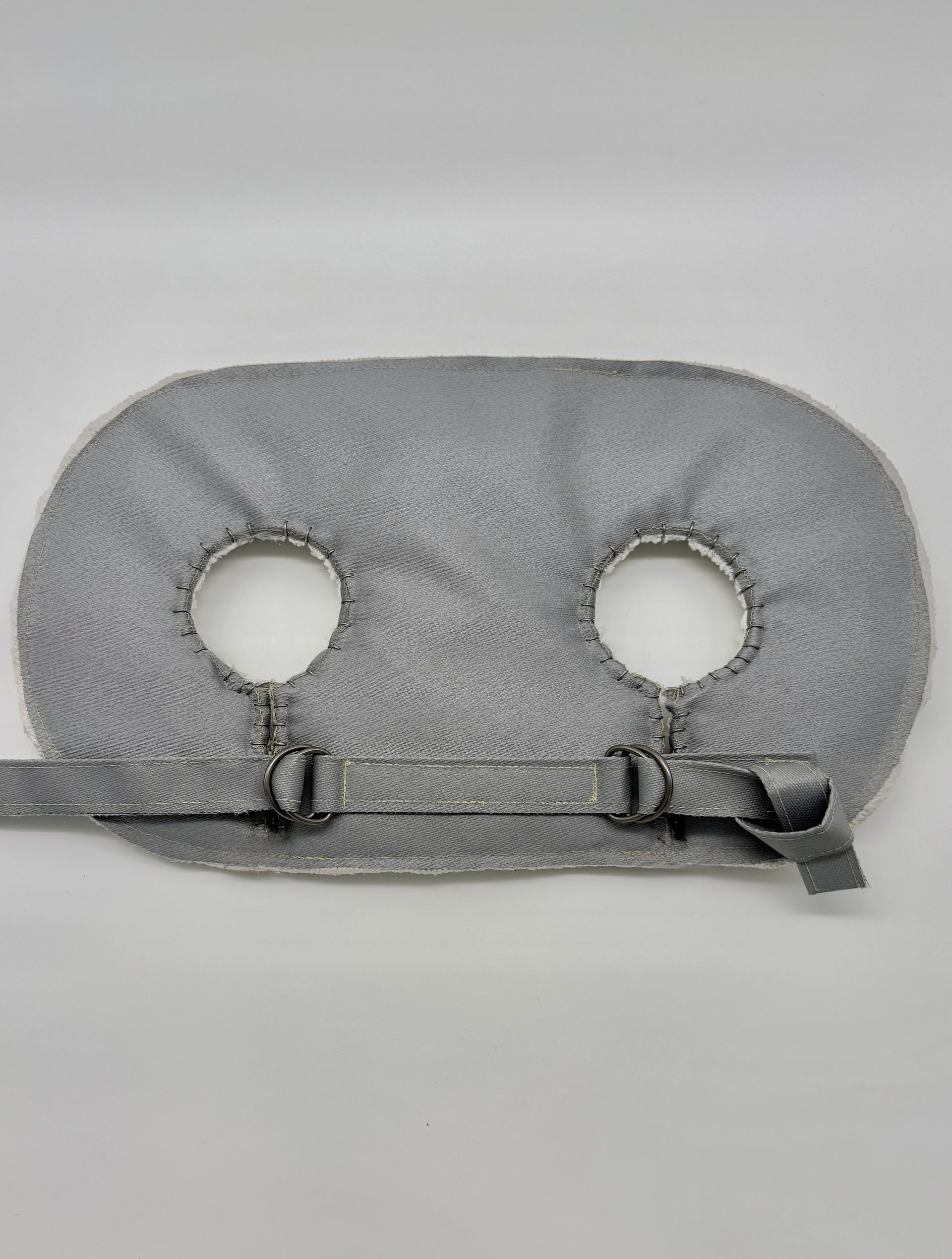 Gray cushion with two circular holes and black straps on a white background