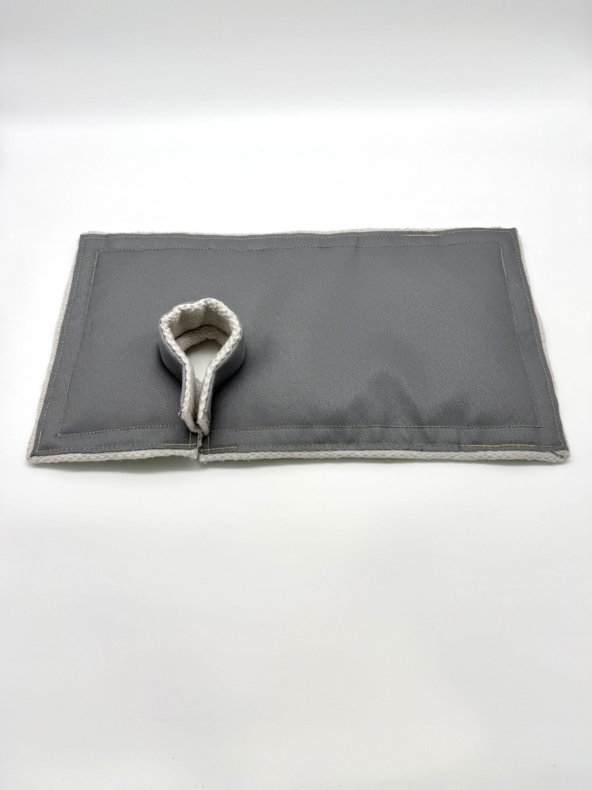 Gray textured placemat with a small looped gray cord or ribbon near the lower left corner