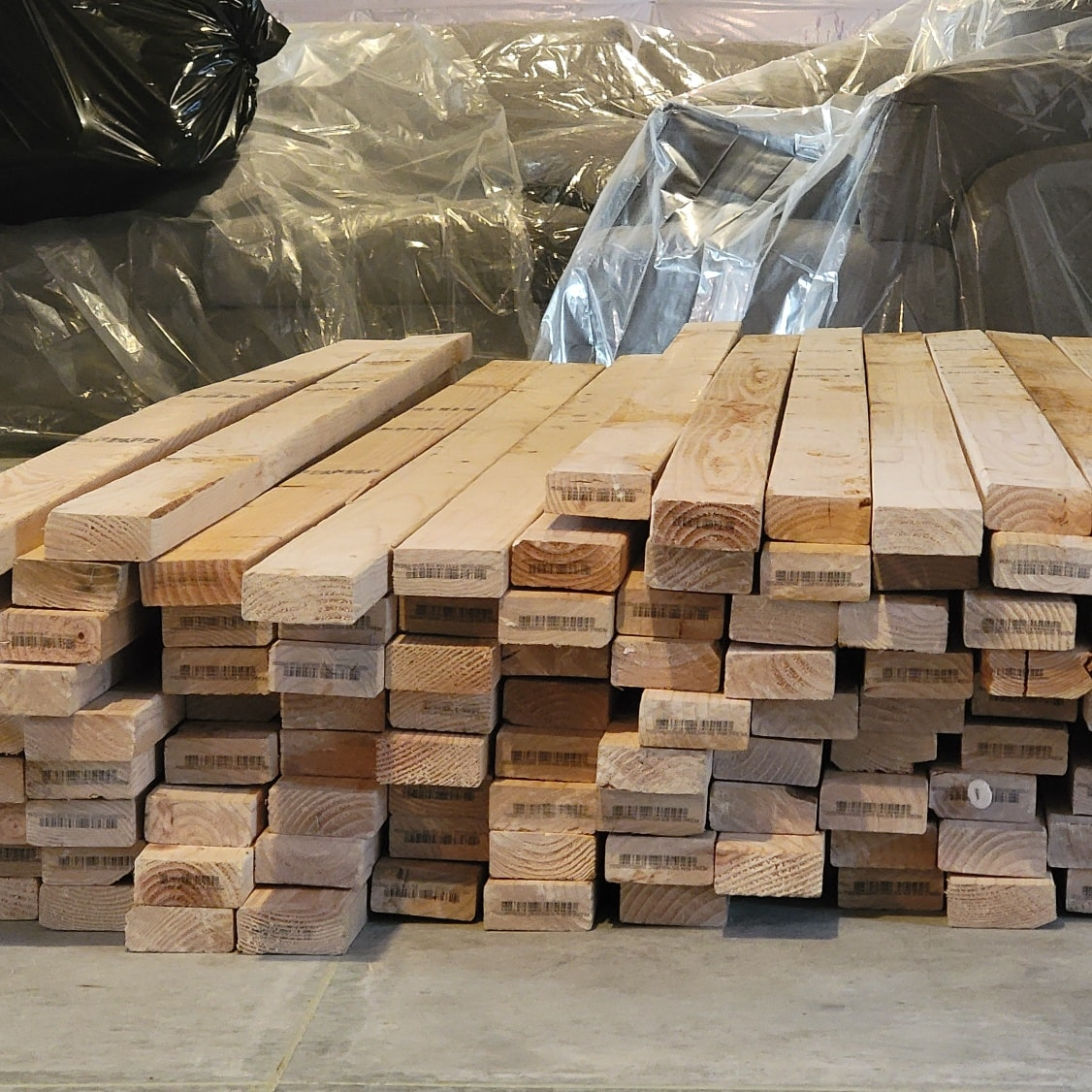 Pile of wooden lumber in a storage area; neutral lighting.