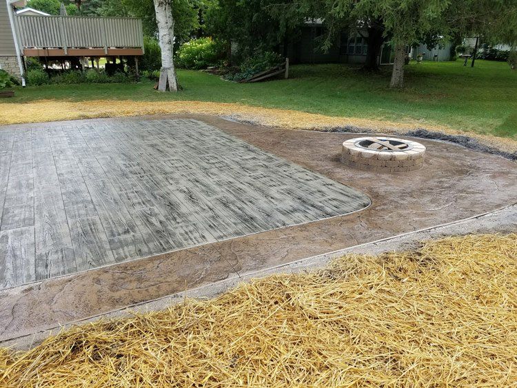 A concrete patio with a fire pit in the middle of it.