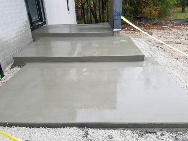 A concrete walkway is being built in front of a house.