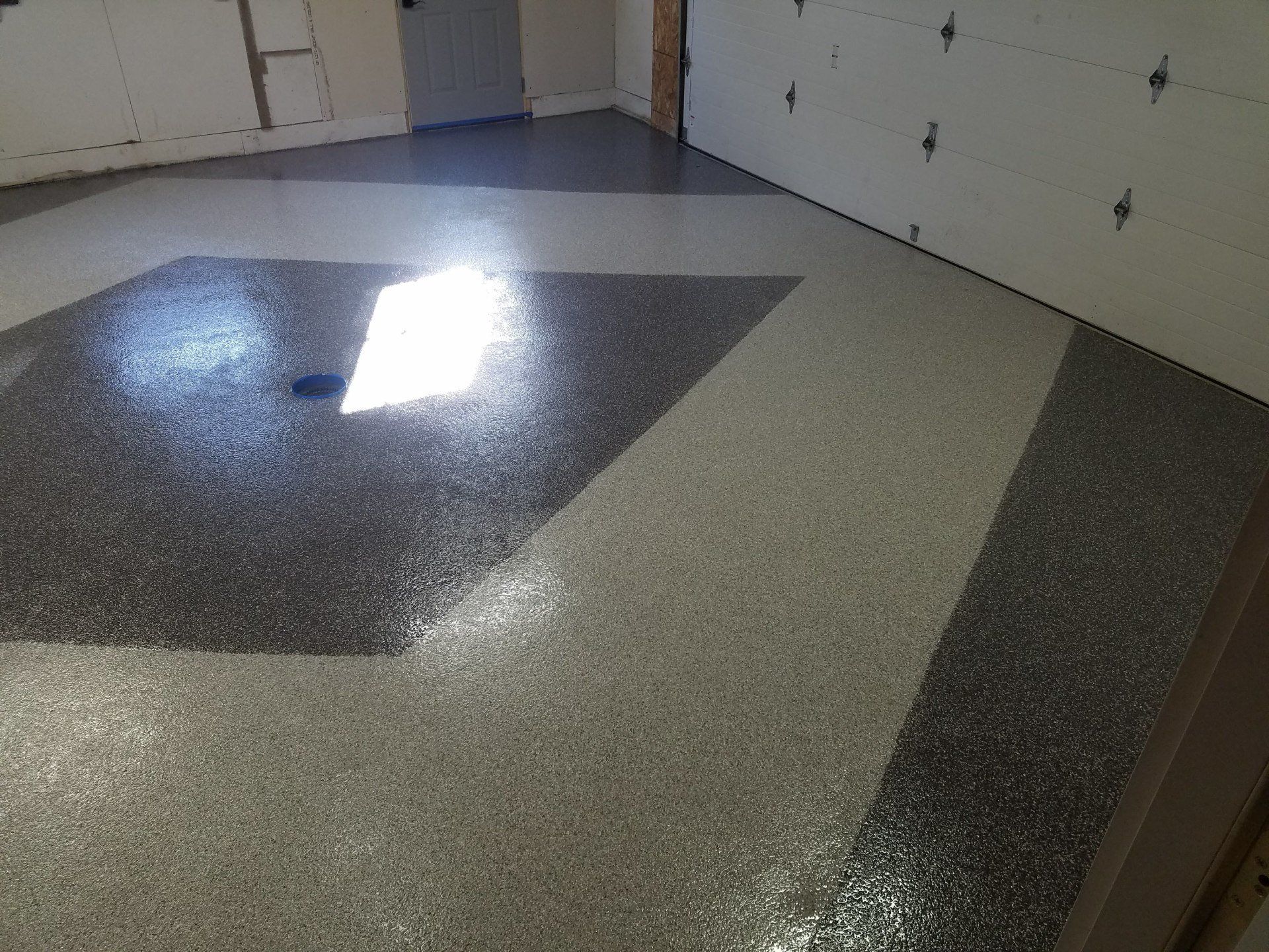 A garage with a geometric pattern on the floor and a garage door.
