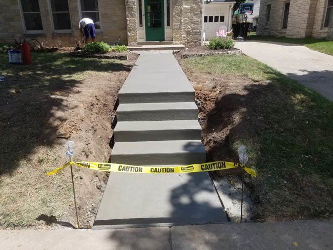 A concrete walkway is being built in front of a house