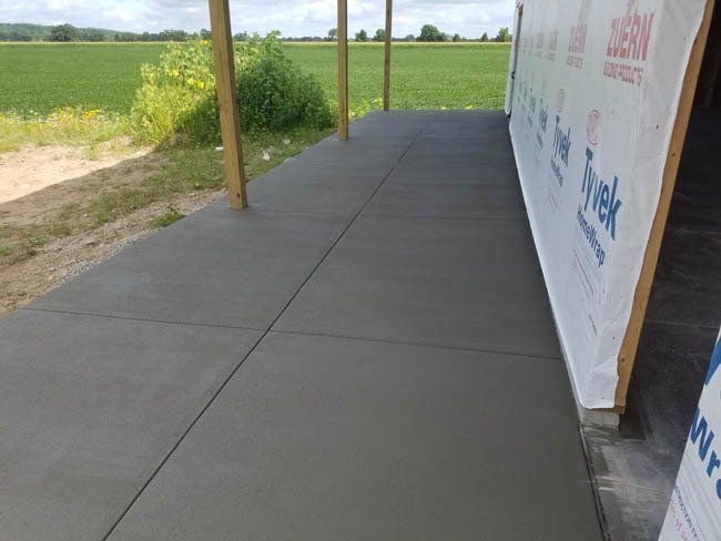 A concrete walkway leading to a building with a field in the background.