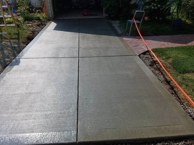 A concrete driveway is being built in front of a garage