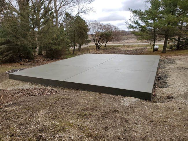 A large concrete slab is sitting in the middle of a dirt field.