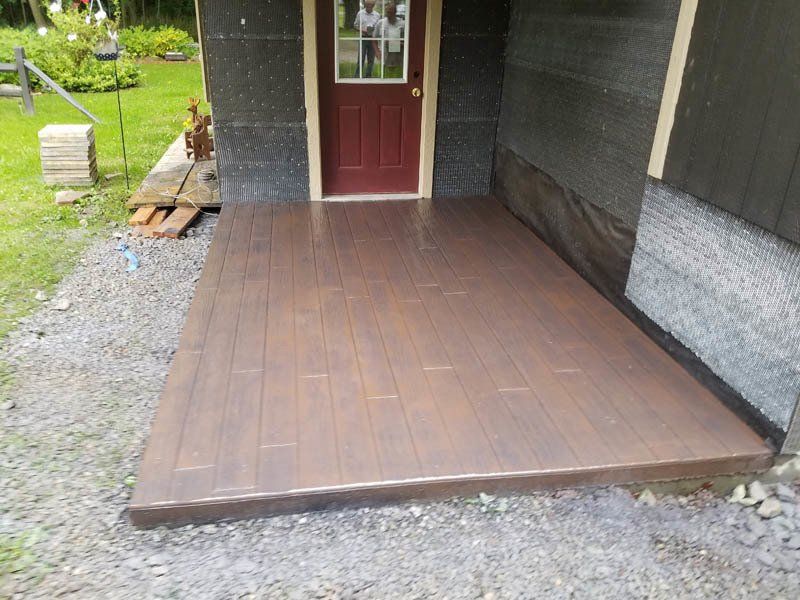 A concrete porch with a red door in the background