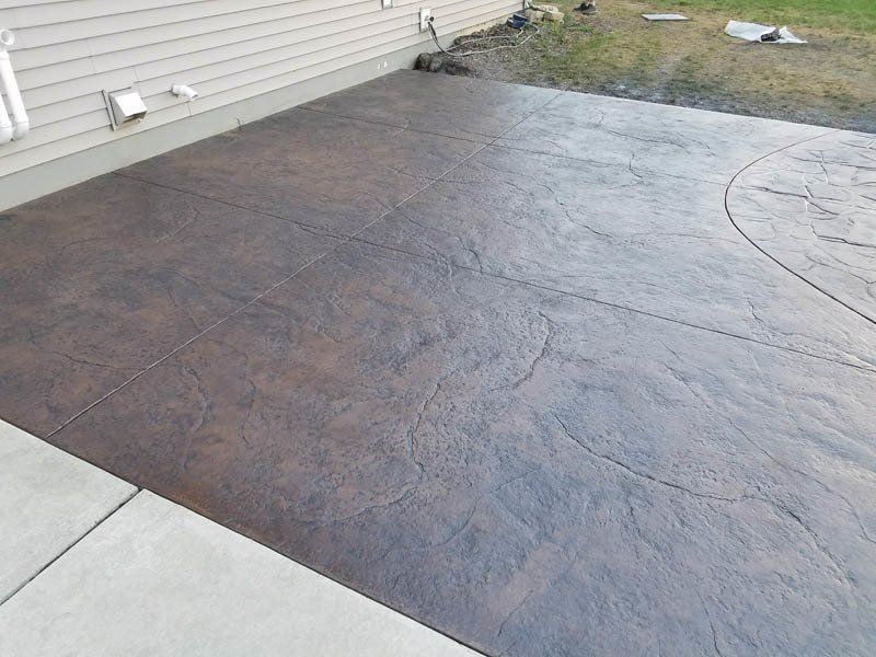 A concrete driveway with a brown stain on it is next to a house.