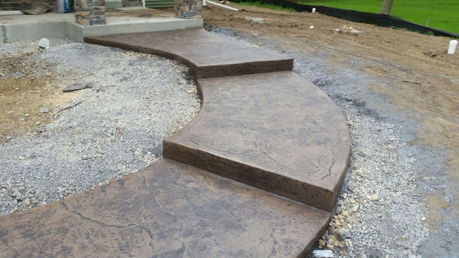 A curved concrete walkway with steps leading up to a house.