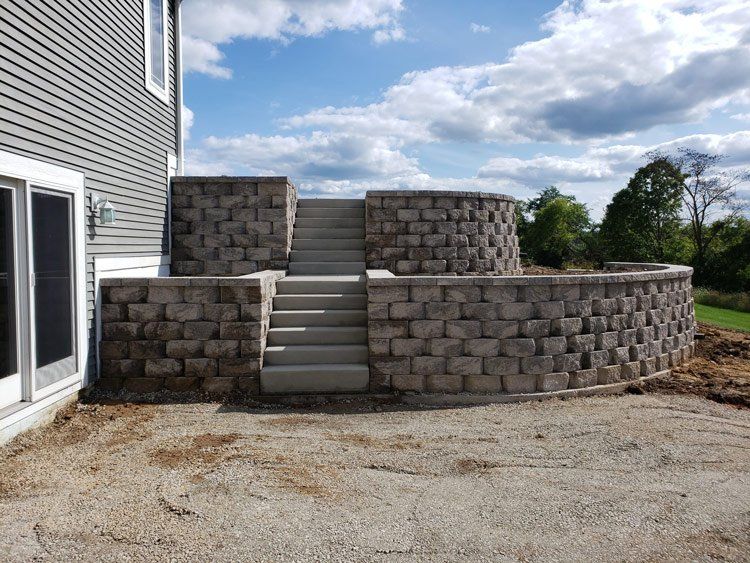 A brick wall with stairs leading up to it in front of a house.