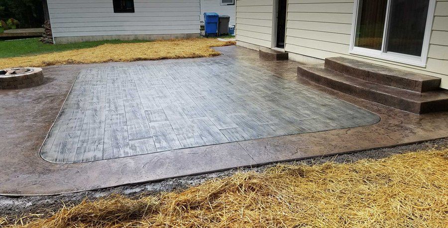 A patio with steps and a fire pit in front of a house.