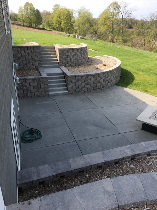 A patio with stairs and a fire pit in the backyard of a house.