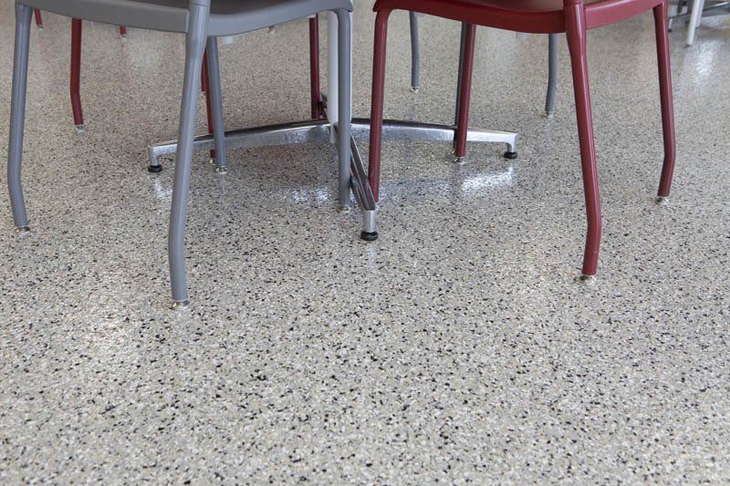 Three chairs are sitting under a table on a concrete floor.