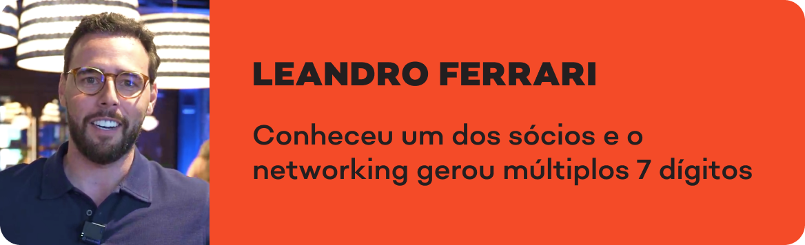 Um homem de óculos e barba está parado em frente a uma placa que diz leandro ferrari.