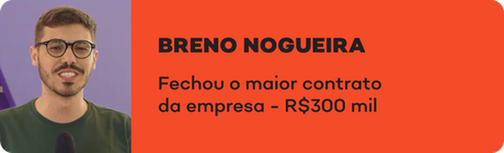 Um homem de óculos está parado em frente a uma placa laranja que diz breno nogueira.