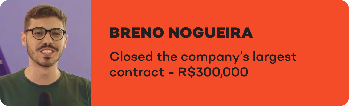 Um homem de óculos está parado em frente a uma placa que diz breno nogueira fechou o maior contrato da empresa