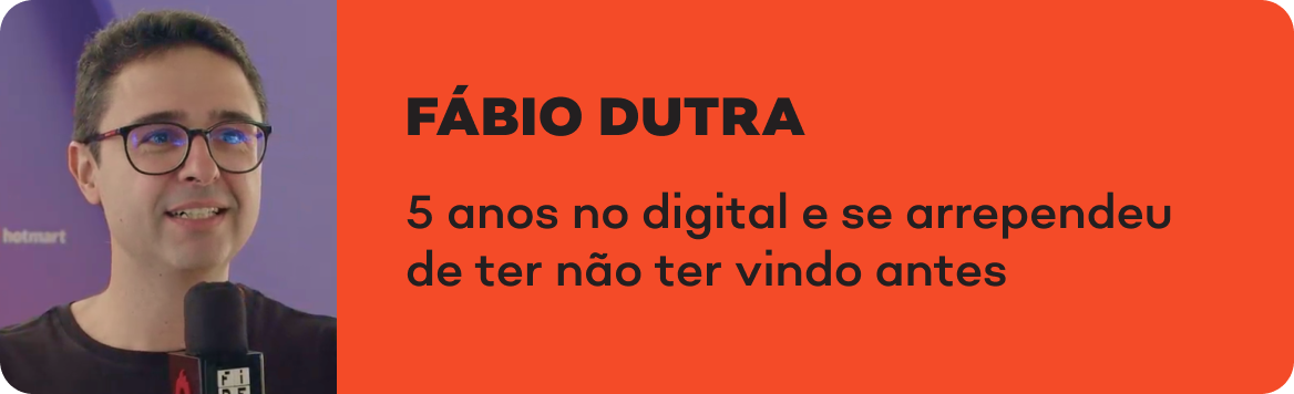 Um homem de óculos está segurando um microfone e sorrindo.