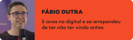 Um homem de óculos está segurando um microfone e sorrindo.