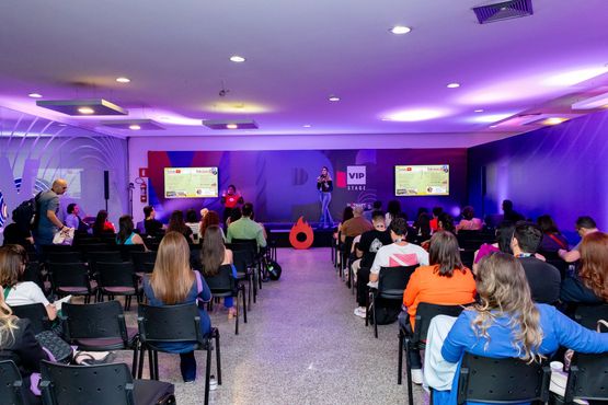 Um grupo de pessoas está sentado em cadeiras em frente a um palco em uma conferência.