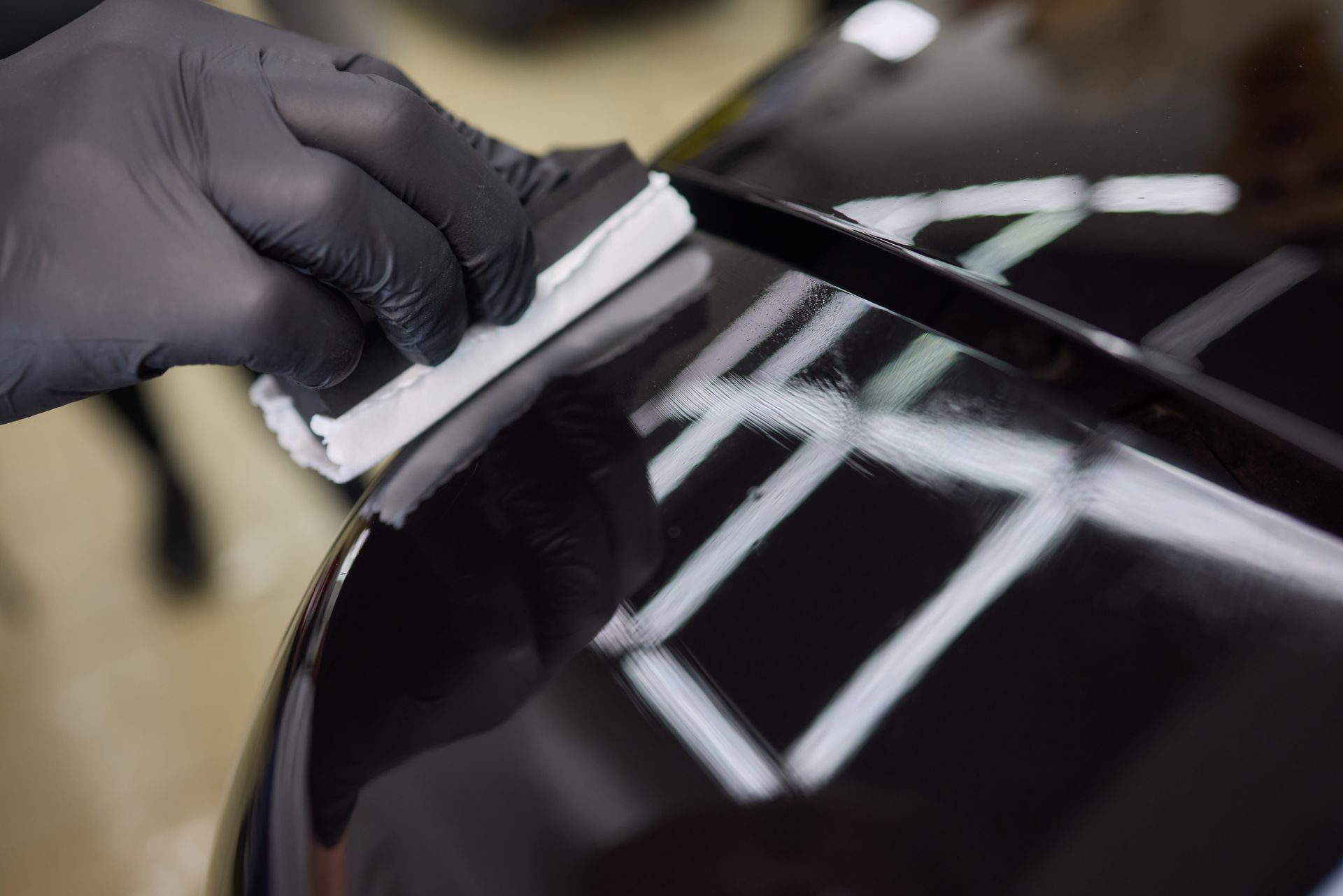 A person is polishing a black car with a ceramic coating.