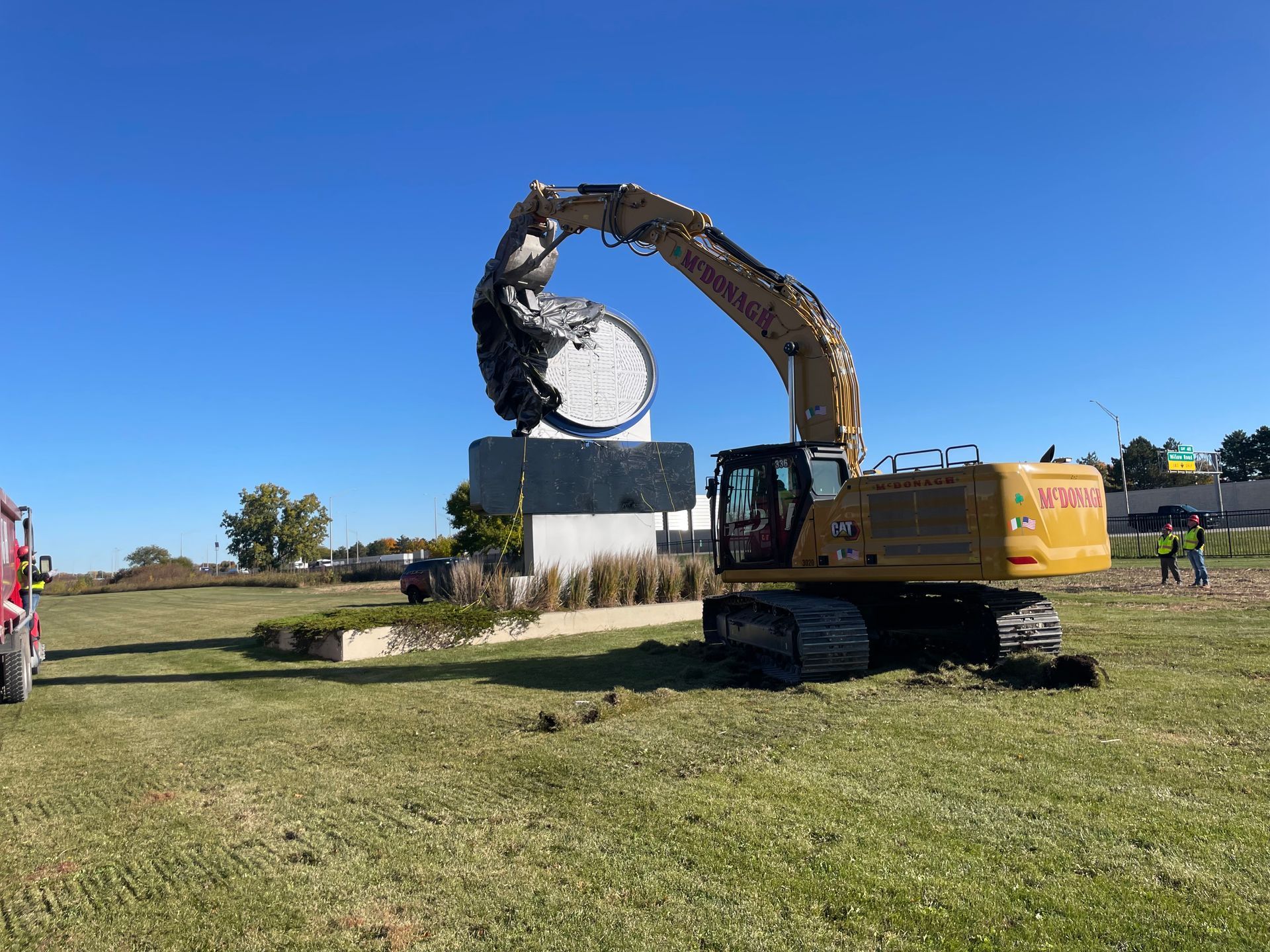 A large excavator is digging a hole in a grassy field.