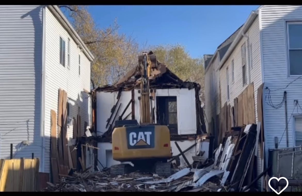 A house is being demolished by a cat excavator.