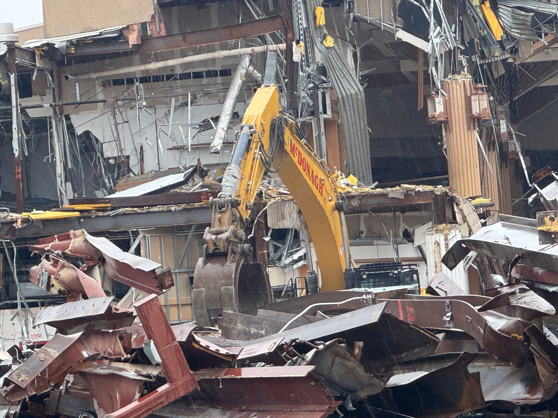 A yellow excavator demolishing a building, surrounded by debris in Chicago, IL.