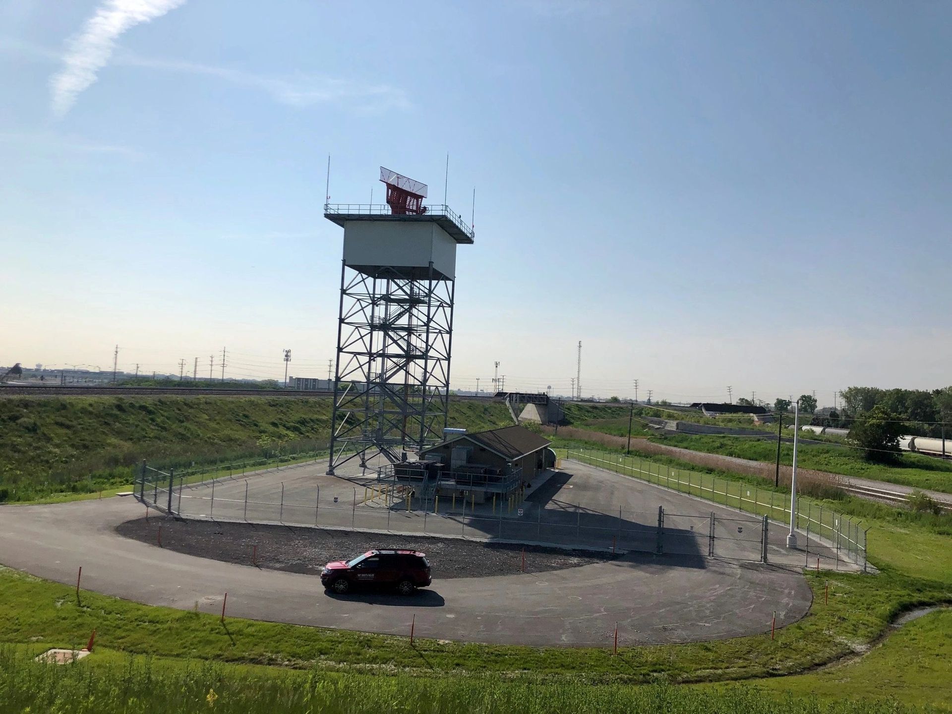 A car is parked in a parking lot in front of a tower.