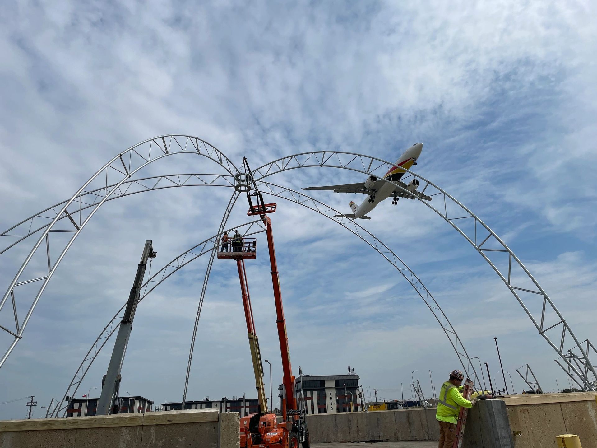 A large airplane is flying over a construction site