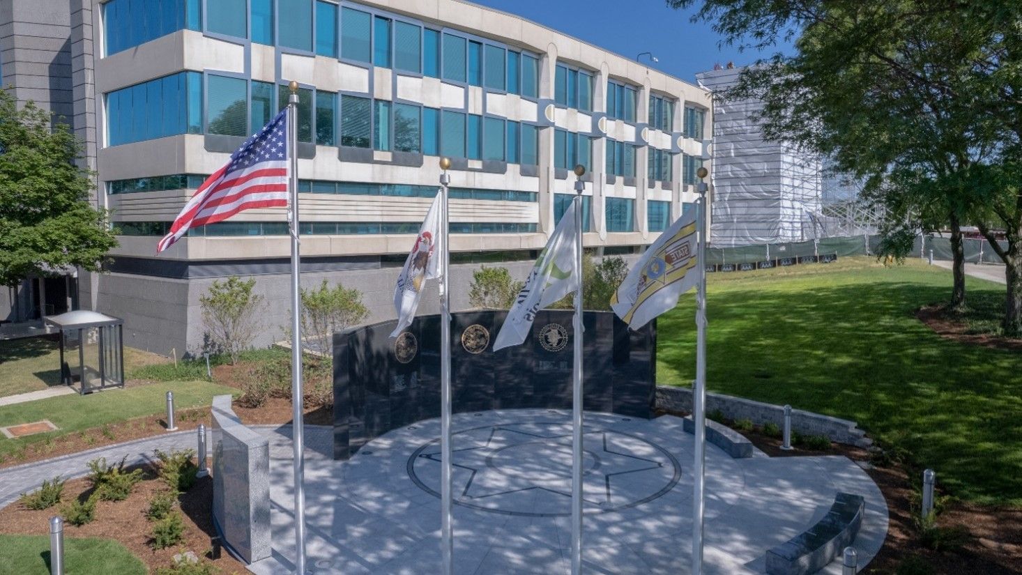 A group of flags are flying in front of a building.