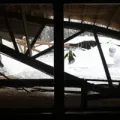 A person is skiing down a snow covered slope in the attic of a building.