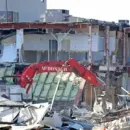 A red crane is being used to demolish a building.