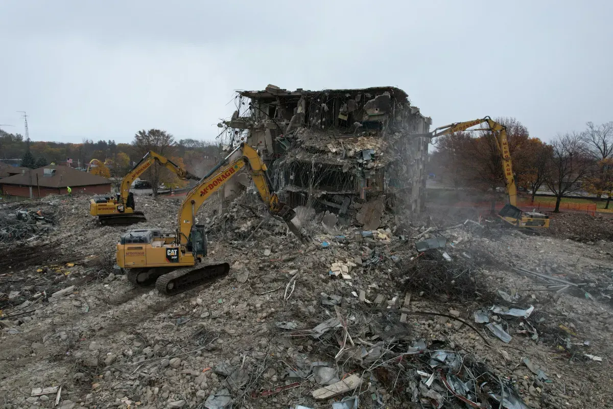 A group of construction vehicles are demolishing a building.