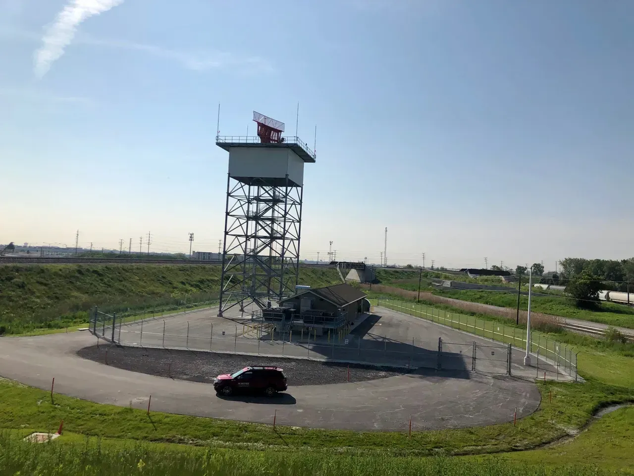 A car is parked in front of a tower in a parking lot.